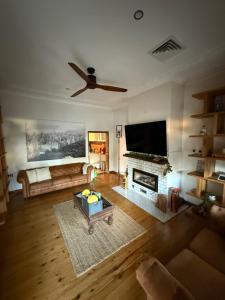 a living room with a ceiling fan and a fireplace at Secret River Cottage in Windsor
