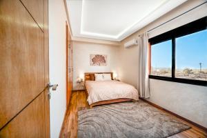 ein Schlafzimmer mit einem Bett und einem großen Fenster in der Unterkunft Élégant avec Parking - Guéliz Hivernage in Marrakesch