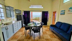 a kitchen with a table and a blue couch at Grandvistasuites Tobago in Scarborough
