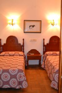 a hotel room with two beds and a table at Hotel Restaurante Toruño in El Rocío