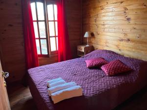 a bedroom with a purple bed with towels on it at Complejo de cabañas El Mangrullo in Larroque