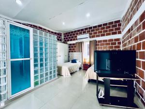 sala de estar con TV y pared de ladrillo en Hospedaje Santaisa, en Cali