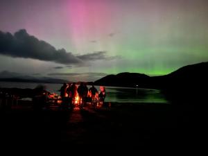 a group of people standing around a bonfire under a rainbow at Red Deer Cottage at Fanans in Oban