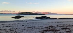 a beach with some rocks in the water at Red Deer Cottage at Fanans in Oban