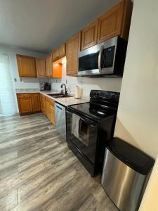 een keuken met houten kasten en een zwarte kookplaat bij Spacious Stay near Lambeau in Green Bay