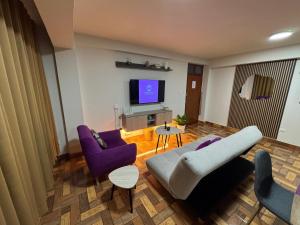 a living room with purple furniture and a flat screen tv at Solena Apartamentos Tacna in Tacna
