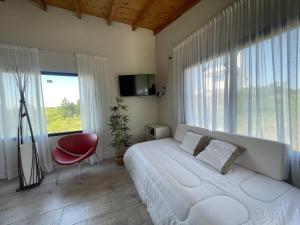 a bedroom with a large white bed and a red chair at Verdena in Villa Amancay +35 photos