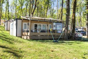 a tiny house with a porch on a yard at Camping Saint Avit Loisirs in Journiac