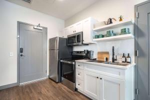 Una cocina con gabinetes blancos y un refrigerador de acero inoxidable. en Bold and Bright Stay with Cher & Etta James Flair, en Macon