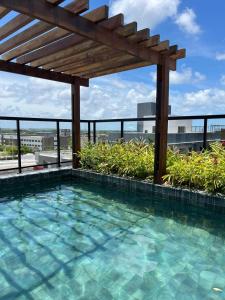 a swimming pool on the roof of a building with a pergola at Flat aconchegante à 300m do mar! in Cabedelo