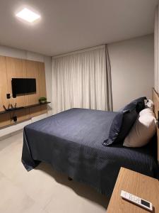 a bedroom with a bed and a flat screen tv at Flat aconchegante à 300m do mar! in Cabedelo