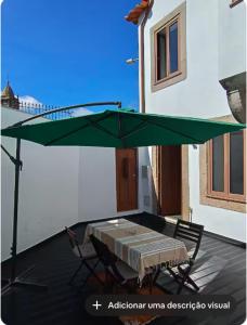 a green umbrella over a table and chairs on a patio at Porto Histórico - pet friendly in Porto