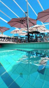 a pool of water with umbrellas and tables and chairs at Céu Beach club in Barra de Guaratiba