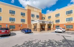 a building with two cars parked in a parking lot at Extended Stay America Suites - Chicago - Midway in Burbank