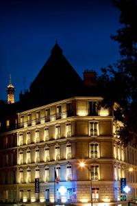 - un grand bâtiment blanc avec des lumières la nuit dans l'établissement Marceau Champs-Elysées, à Paris