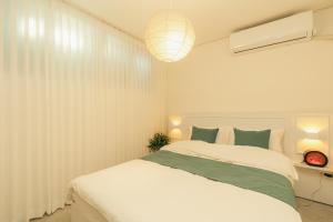 a bedroom with a large white bed and a lamp at 잠실Cozy BnB 가족친구여행 감성숙소 역세권 선착순 무료주차 #롯데타워 #KSPO #석촌호수 #서울아산병원 in Seoul