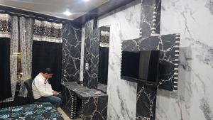 Un hombre sentado en una silla en una habitación con un televisor. en Heritage Heaven home stay 1 black, en Varanasi 15 fotos más