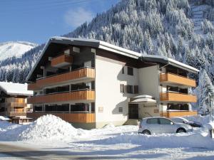 沙泰勒Studio in Châtel near Portes du Soleil Ski Area的雪地中的一座建筑,前面有停车位