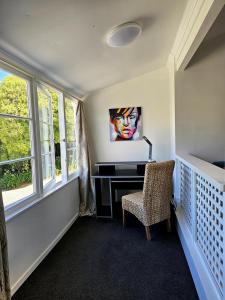a room with a desk and a chair and windows at Charming Getaway Relax and Unwind in Nelson
