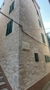 un edificio de piedra con ventanas verdes y un cartel en él en Seaside holiday house Sibenik - 23990, en Šibenik