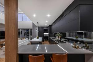 eine Küche mit schwarzen Schränken und einer großen Insel in der Unterkunft 4Bedroom Luxury home with Comfort & Stylish in Weston Creek