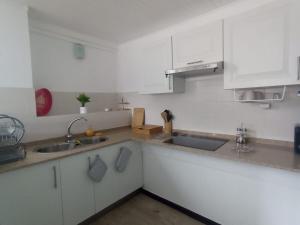 a kitchen with white cabinets and a sink at Saphir Caraïbe in Fort-de-France