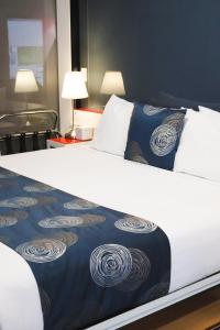 a large white bed with a blue and white blanket at Stay Motel - Formerly Room Motels Gympie in Gympie