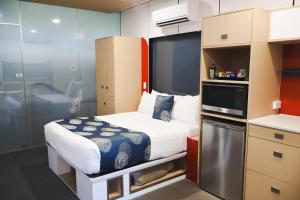 a small room with a bed and a microwave at Stay Motel - Formerly Room Motels Gympie in Gympie