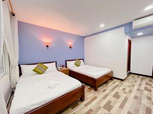 a bedroom with two beds and a purple wall at Kampot Orkide Guesthouse in Kampot