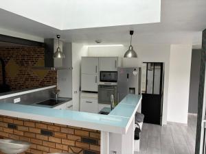 a kitchen with white cabinets and a blue counter top at Maison à proximité de la mer in Trévou-Tréguignec