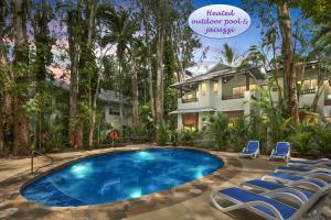 a swimming pool in front of a house with chairs at The Reef Retreat Palm Cove in Palm Cove