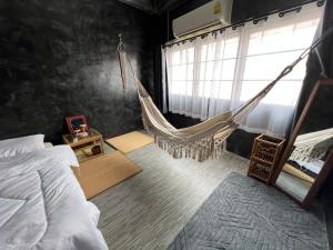 a bedroom with a hammock and a bed and a window at Stay Strays Hostel in Bangkok