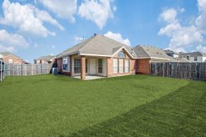 a brick house with a fence in a yard at Gorgeous cozy home in nature serene neighborhood! in DeSoto