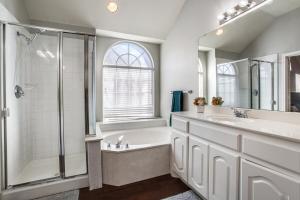 a bathroom with a tub and a sink and a shower at Gorgeous cozy home in nature serene neighborhood! in DeSoto +8 photos