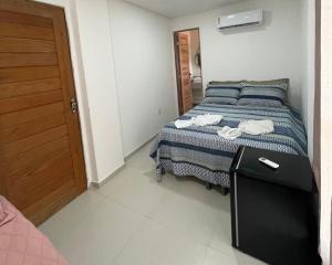 a bedroom with a bed with a black table and a door at Suíte Pôr do Sol 1 - Pé na Areia in Maragogi +2 photos