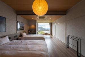 una camera d'albergo con due letti e un lampadario a braccio di 尾道倶楽部 a Onomichi