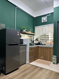 a kitchen with green walls and a refrigerator at Adwa Guesthouse in Keningau