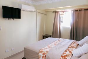 a bedroom with a bed and a television on the wall at BNB Price Vacation Rentals, Corales del Sur, Santo Domingo Este in La Viva +9 photos