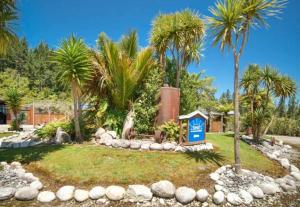 a garden with palm trees and a blue sign at Sunset Accommodation in Westport
