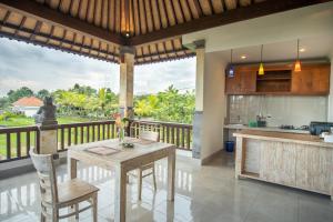 cocina y comedor con mesa y balcón en Suar Villa Ubud, en Ubud