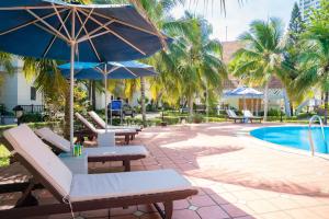 a patio with chairs and umbrellas next to a pool at Lotus Vung Tau Resort & Spa in Vung Tau