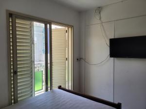 a bedroom with a bed and a window with a television at Hotel CAMACHO in Córdoba