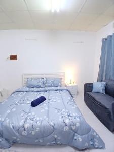 une chambre avec un lit avec une couette bleue et un canapé dans l'établissement Al Ain Blue, à Al-Aïn 5 autres photos