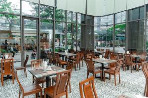 Un restaurante con mesas, sillas y ventanas. en Platinum Orchid Hotel Danang, en Da Nang
