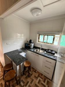 a small kitchen with a sink and a counter with stools at Cabañas en Valdivia in Valdivia