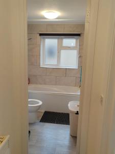 a bathroom with a tub and a toilet and a window at Domasi Flat in New Cross in London +15 photos