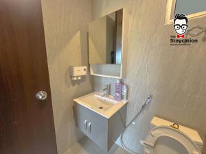 a bathroom with a toilet and a sink and a mirror at Staycation Homestay 65 Liberty Grove Near Airport in Kuching