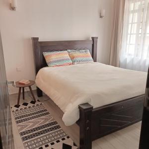 a bedroom with a bed with white sheets and pillows at The Perfect Stay 2BR in Ruaka Near Two Rivers in Nairobi +20 photos