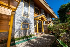 a stone house with yellow columns and windows at 4 Bedroom Log Cabin in Camp John Hay Baguio in Baguio