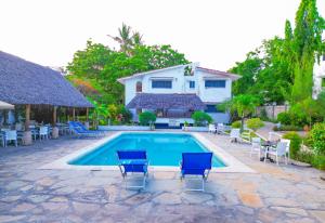 a swimming pool with chairs and a house at Maasai Resort in Mombasa